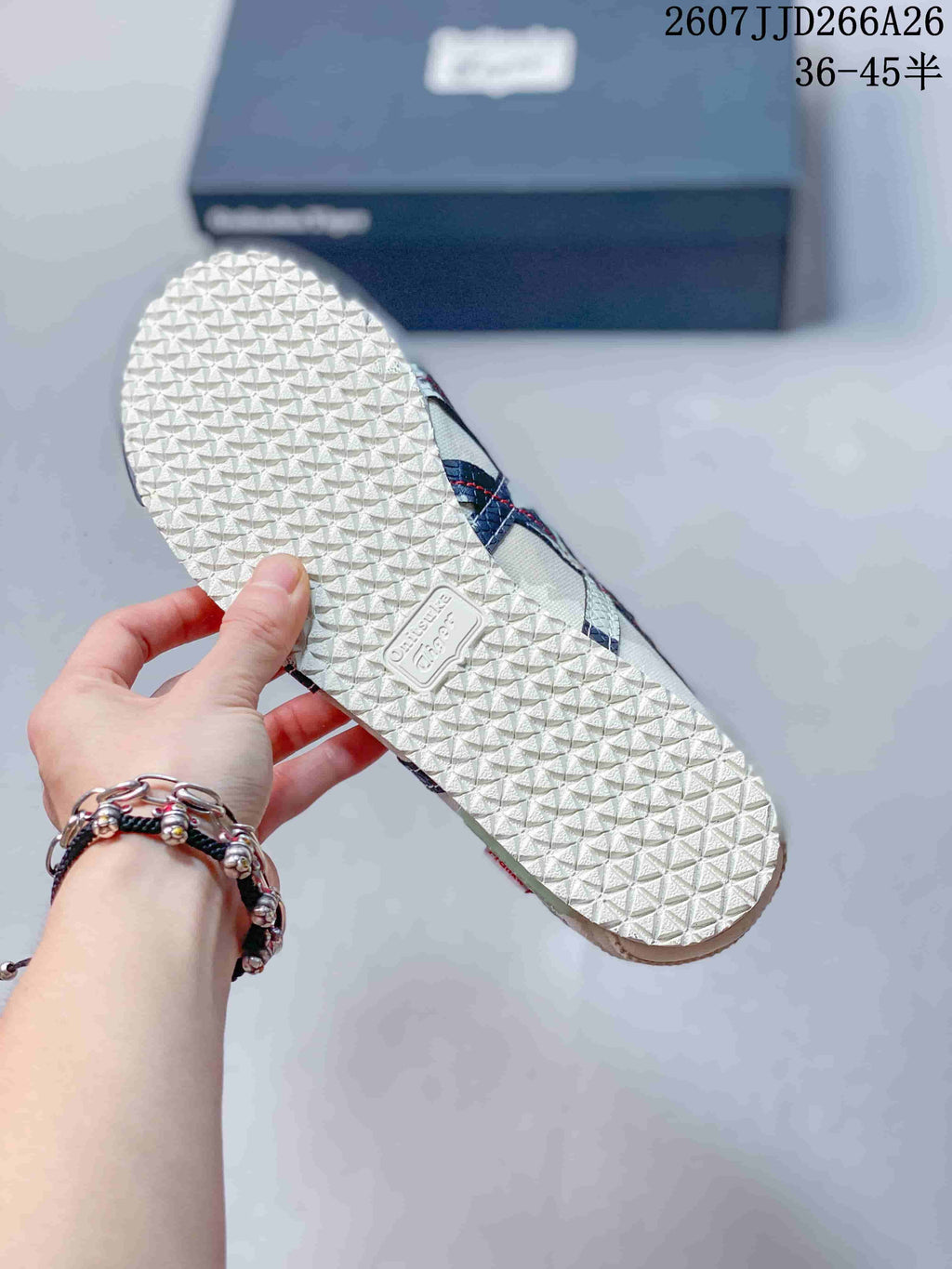 Underside view of an Onitsuka Tiger sneaker showing the textured white rubber outsole and central brand panel.
