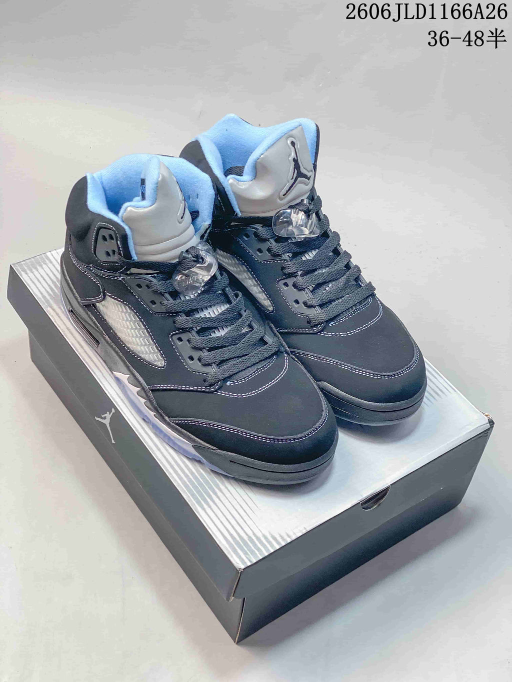 Pair of dark Jordan Air Jordan 5 high-top sneakers with light blue accents, shown on a shoebox.