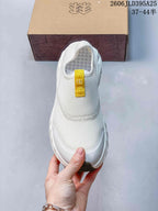 Top view of the white slip-on shoe with a yellow pull tab and mesh-like upper.