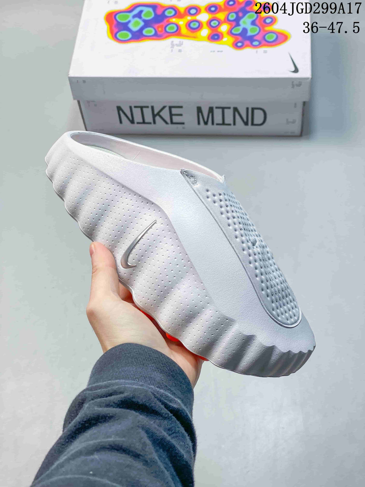 Side view of a white Nike Mind slide showing the perforated upper, side logo, and ridged outsole.