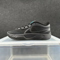 Side view of an all-black Nike lace-up sneaker with a sculpted sole and a small turquoise accent near the tongue.