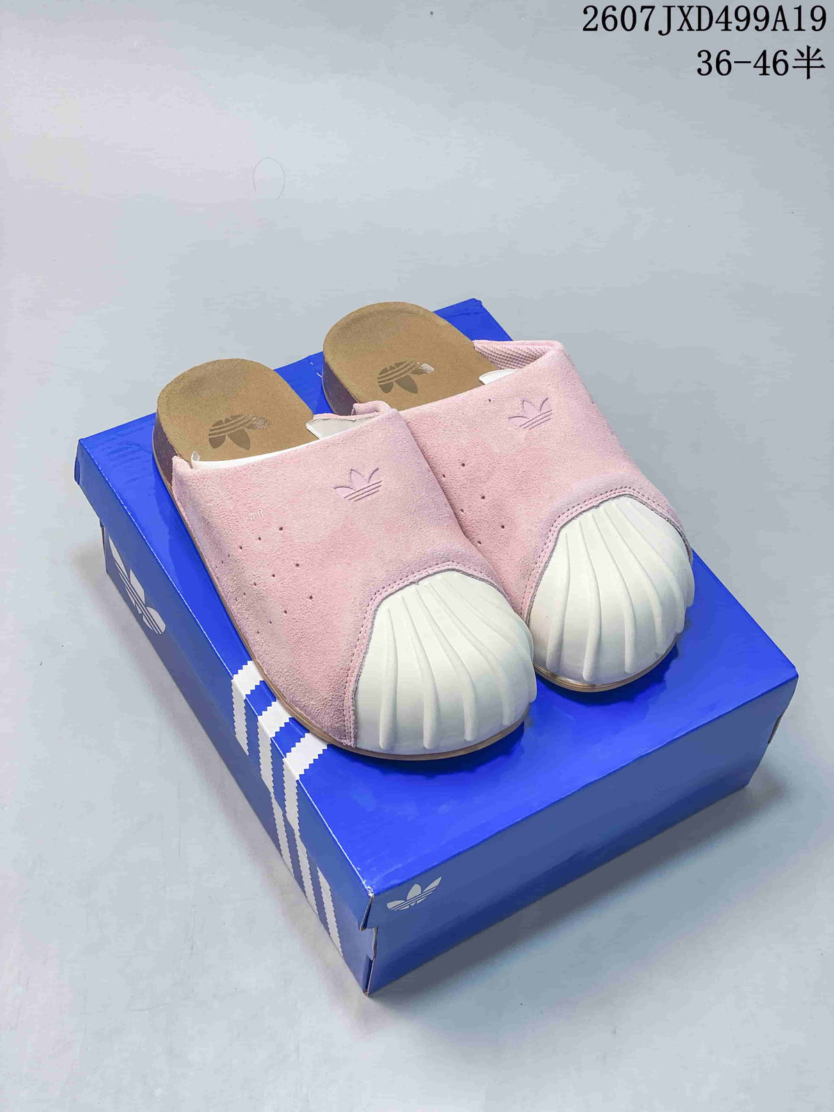 Pink adidas Adimule mule slides with ribbed white toe details displayed on a blue shoebox.