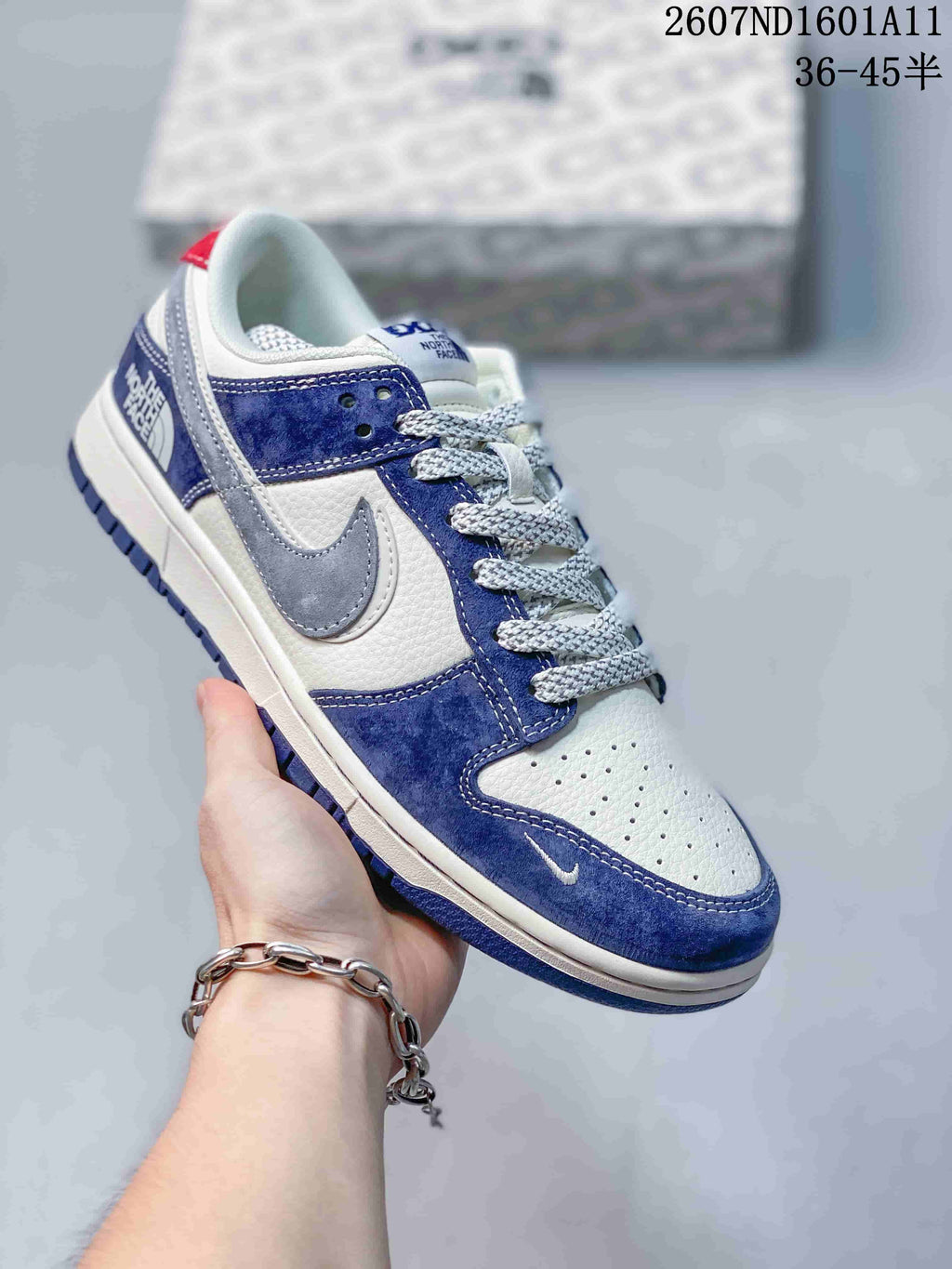 Angled side view highlighting the blue and white upper, gray swoosh-style overlay, textured laces, and heel branding.