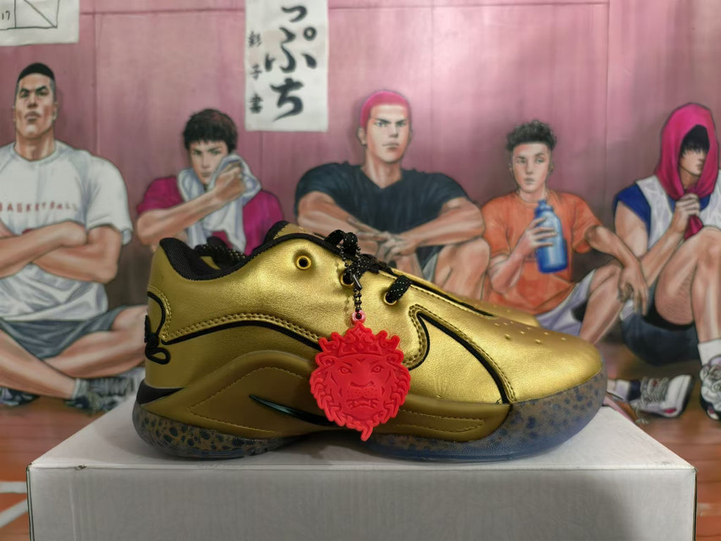 Side view of a metallic gold Nike basketball shoe with black trim and a red charm
