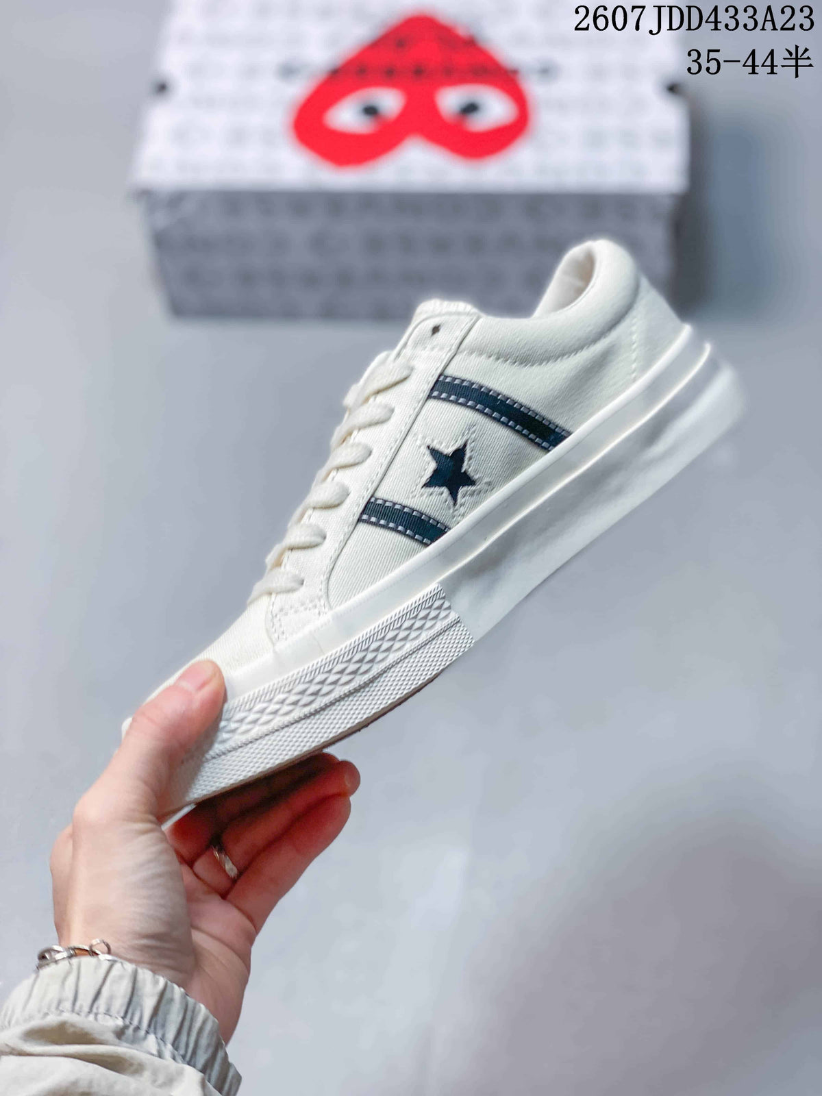 Side profile showing the off-white low-top silhouette, dark stripes, star detail and white rubber sole.