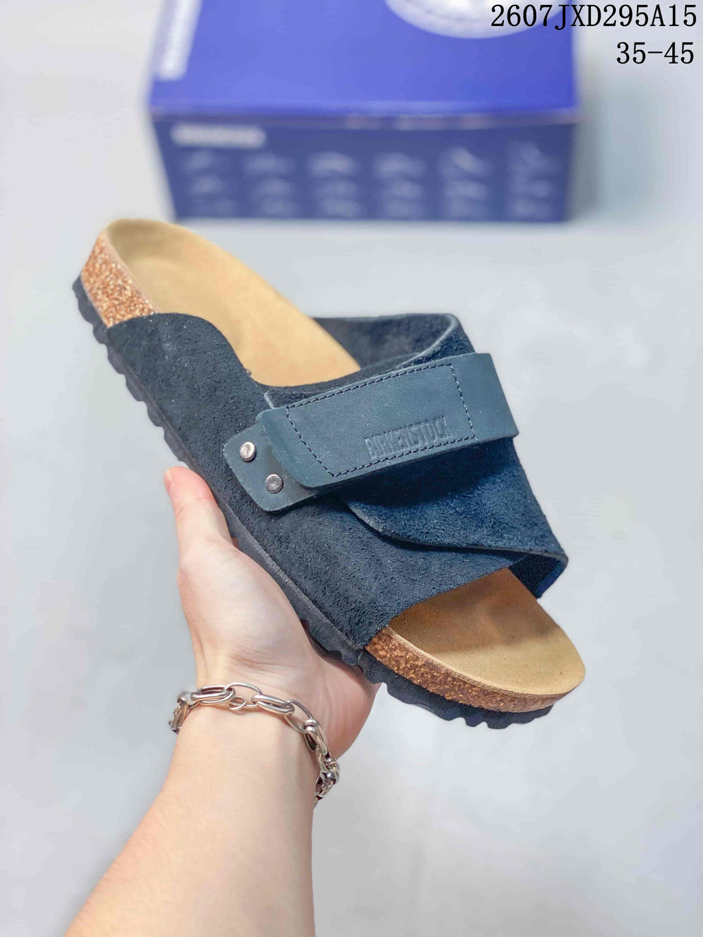 Angled close view of the dark blue sandal with adjustable buckle, open toe and cork-look footbed sidewall.