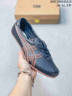 Black low-top sneaker with brown side stripes, black laces, and a tan textured outsole.