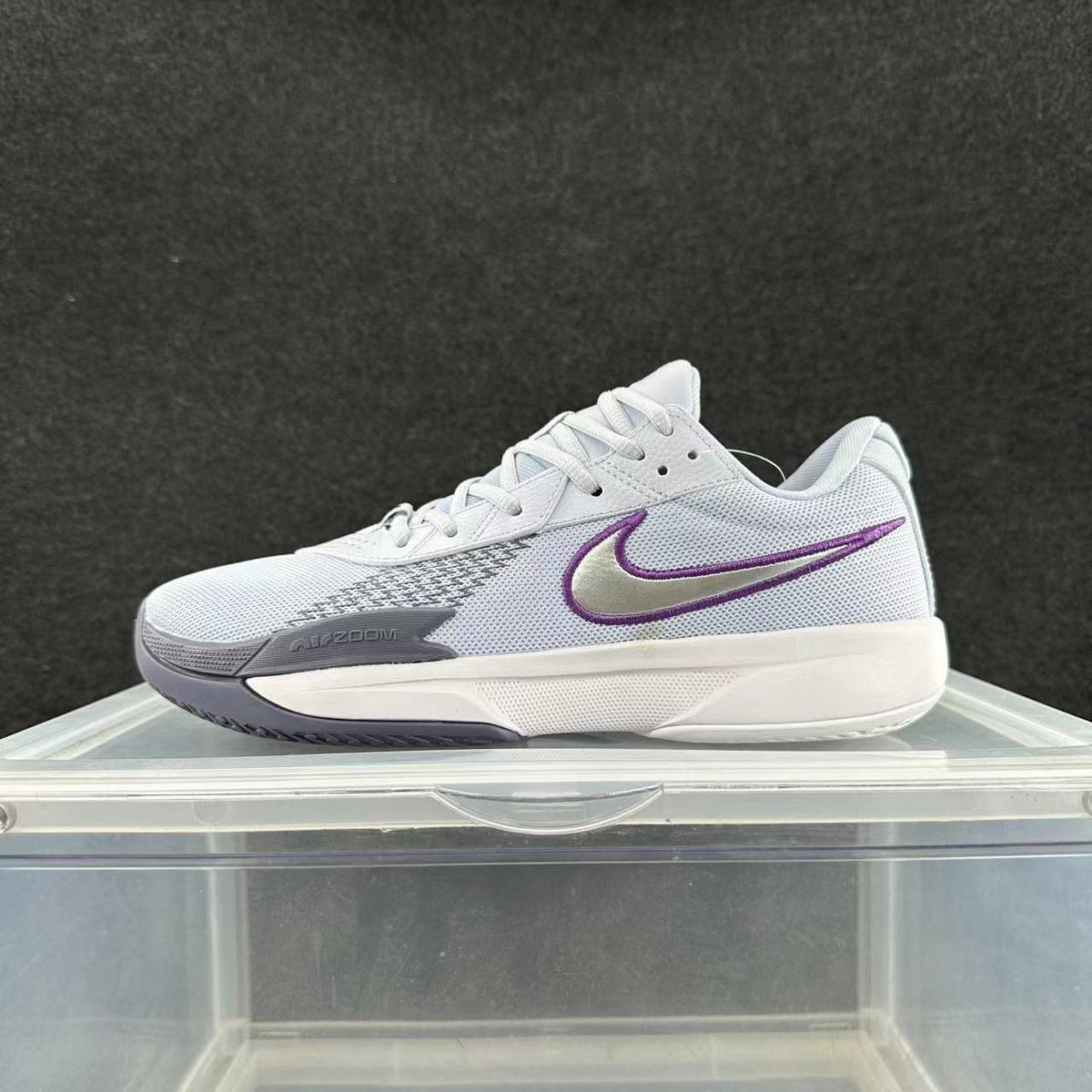 Side view of a white Nike Zoom sneaker with gray forefoot detailing, a purple-outlined Swoosh and a white midsole.