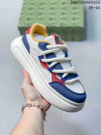 Close angled view of the multicolor low-top sneaker with white base panels, navy and red overlays, white laces and a thick sole.