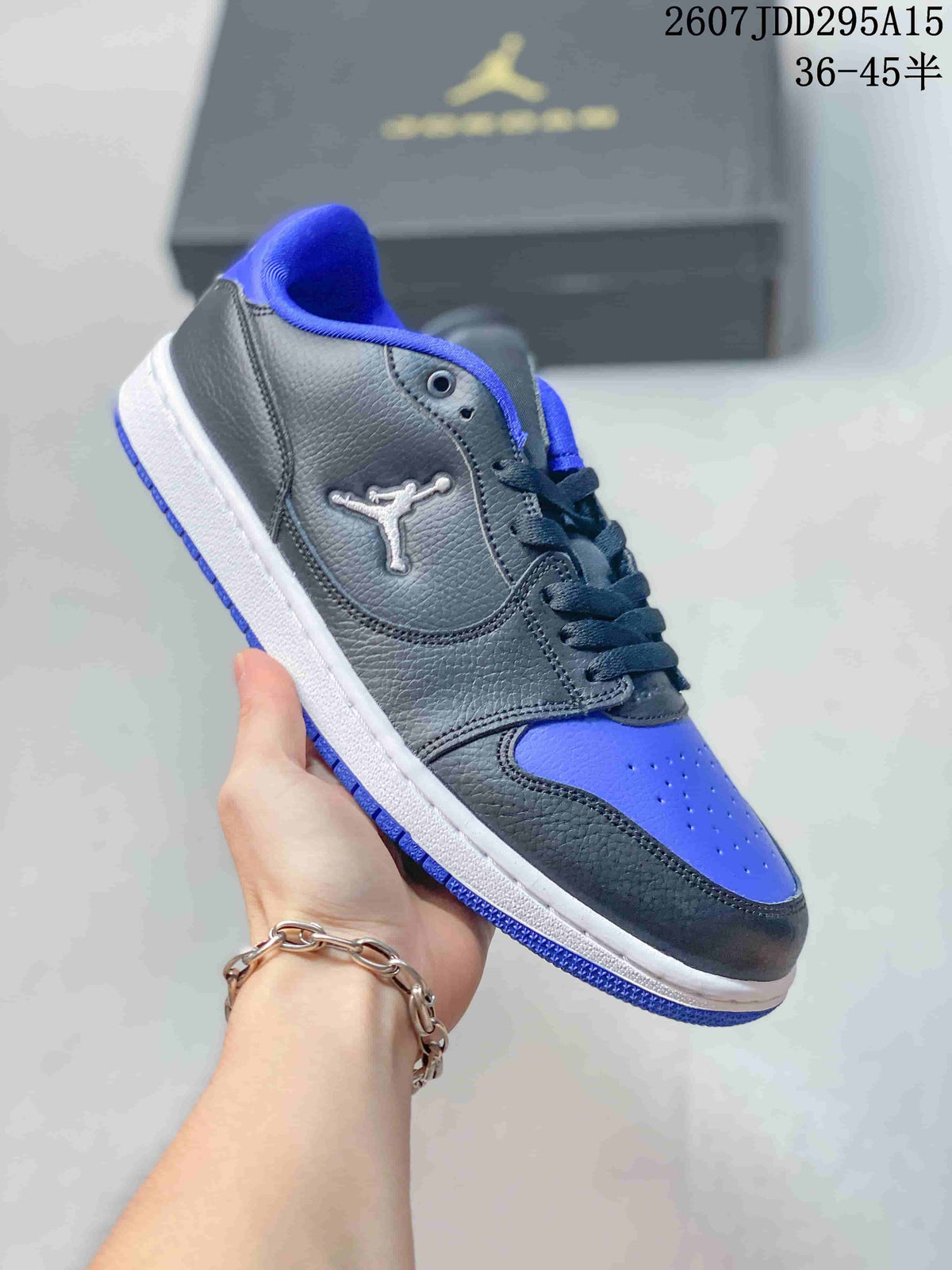 Black and blue low-top Jordan sneaker held at an angle, with blue lining, blue toe panel, and blue outsole accents.