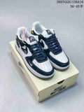 Pair of black and white Nike Air Force 1 sneakers displayed on a shoebox, showing contrasting overlays, dark laces, and white perforated toe boxes.