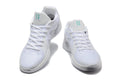 Pair of white Nike Sabrina basketball shoes shown from the front with teal tongue accents.