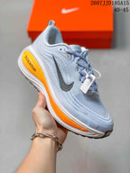 Close side view of a light blue-white Nike Vomero Plus sneaker with an orange sole accent.