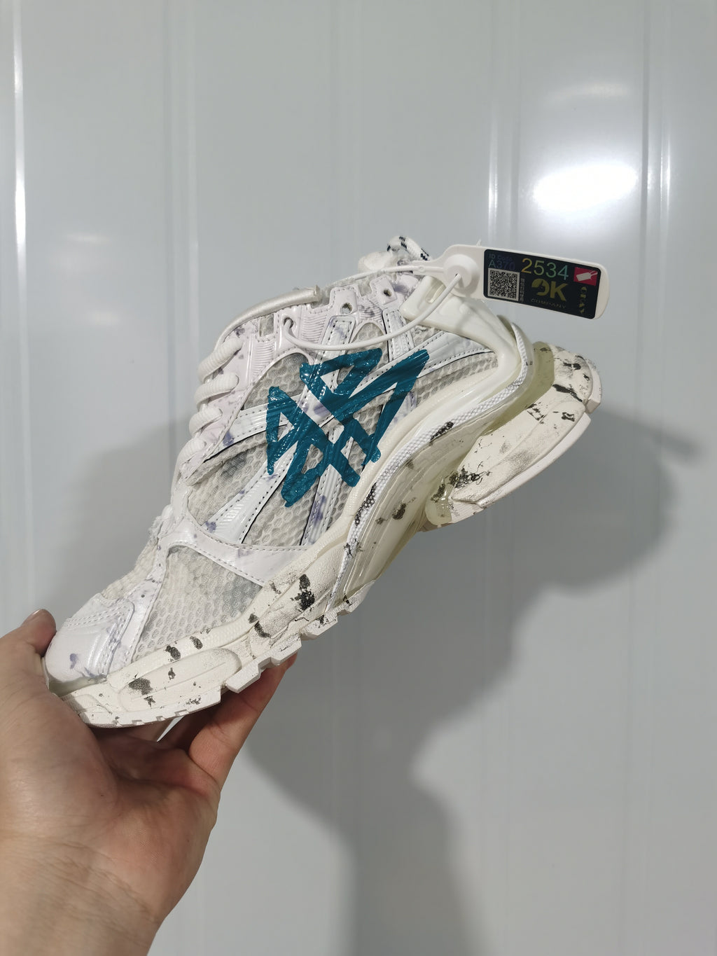 Top and lateral view of the white and blue Runner sneaker, showing mesh panels, graphic-style overlays, and a sculpted sole.