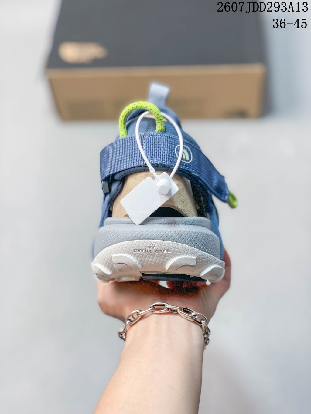 Rear view of one blue-gray sandal showing the heel structure, pull loop, and textured outsole.