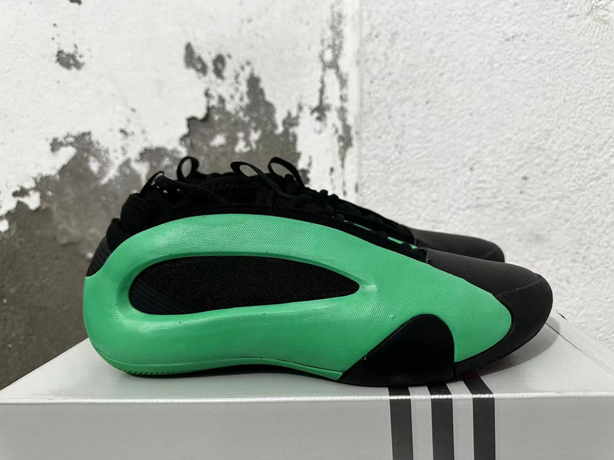 Side view showing the sculpted green panel and black inset on an Adidas basketball shoe.