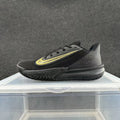 Side view of a black Nike Precision 7 basketball shoe with a gold-tone Swoosh, perforated heel panel, and patterned outsole.