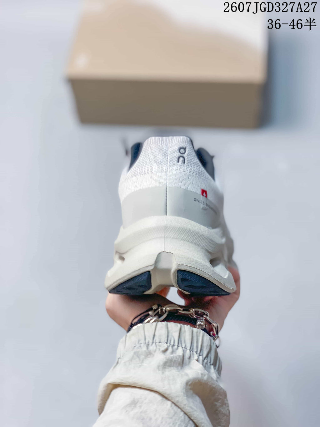 Rear view of a white and gray sneaker showing the padded heel, On branding, and split sole structure.