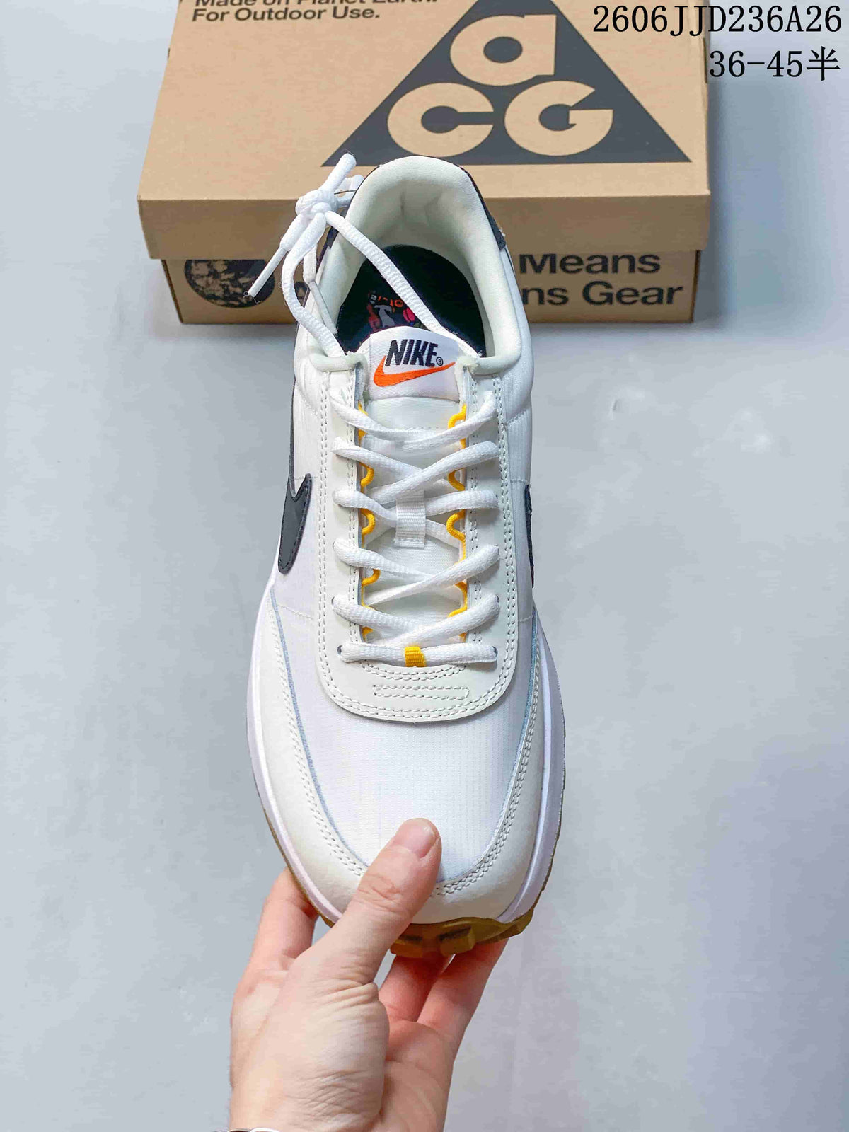 Top view of the white lace-up sneaker showing the tongue branding, yellow eyelet accents, and stitched toe panel.
