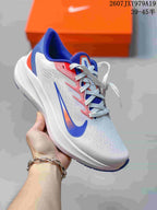 White Nike running sneaker with blue and pink accents, held in front of an orange shoe box.