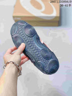 Underside view of a black ASICS sneaker showing the circular-patterned outsole and textured tread.