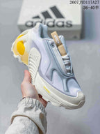 Angled side view showing the layered upper, tan tongue pull, yellow heel detail, and ADIPRENE lettering on the midsole.