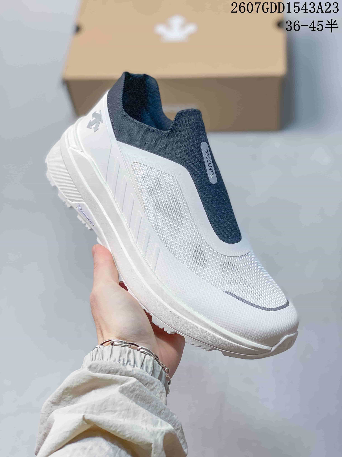 Angled view of the white and navy DESCENTE slip-on sneaker with textured upper panels