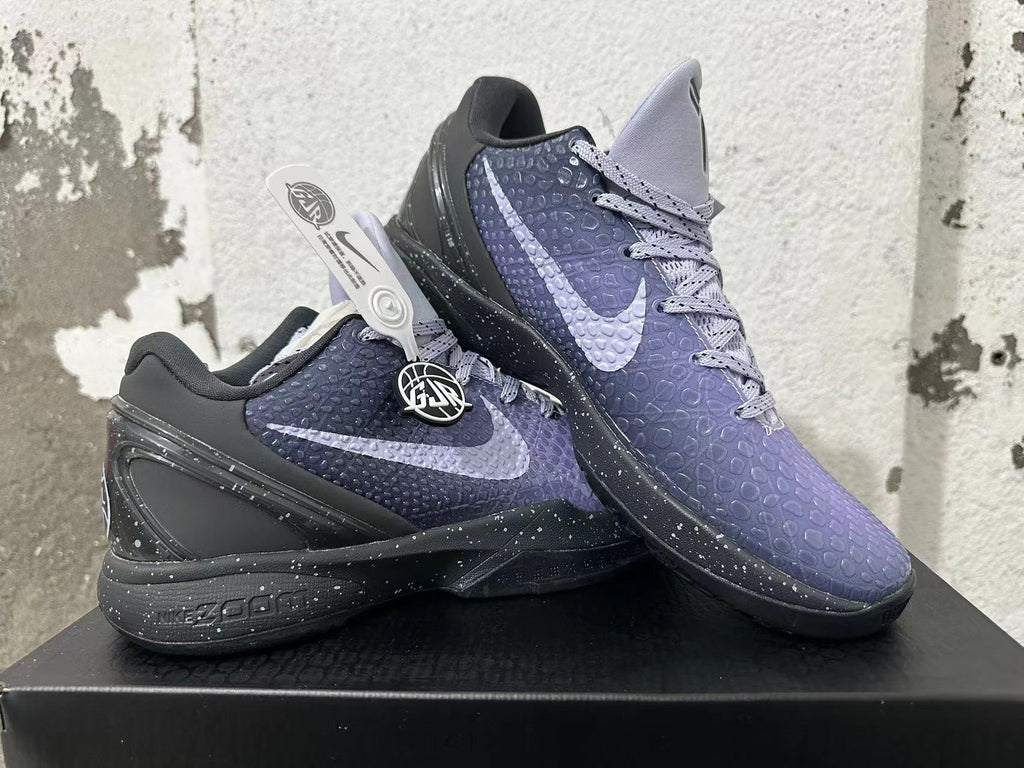 Two purple and black Nike Kobe basketball shoes displayed together, showing side Swooshes and textured uppers.