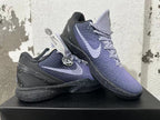 Two purple and black Nike Kobe basketball shoes displayed together, showing side Swooshes and textured uppers.