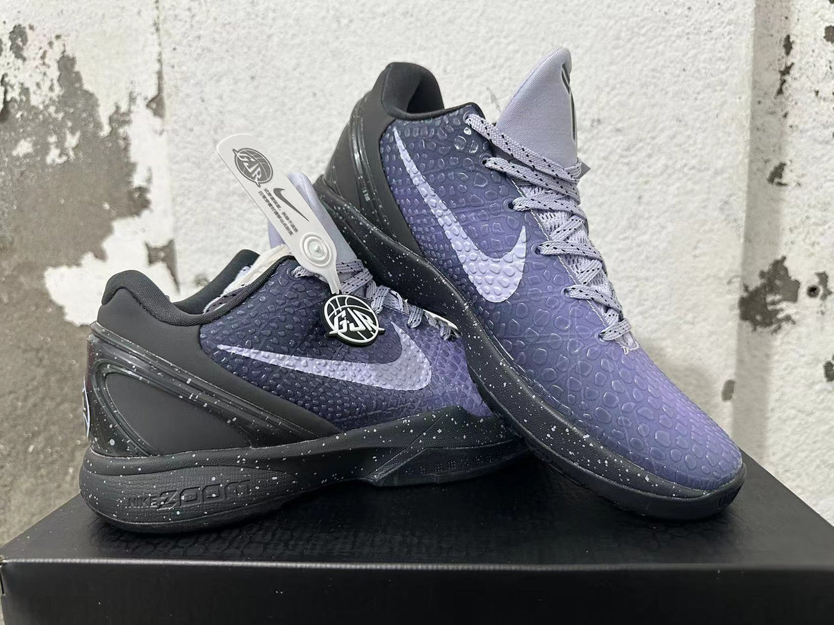 Two purple and black Nike Kobe basketball shoes displayed together, showing side Swooshes and textured uppers.