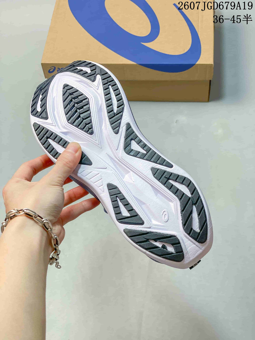 Close view of the sneaker outsole showing a white base with black traction sections and geometric tread patterns.