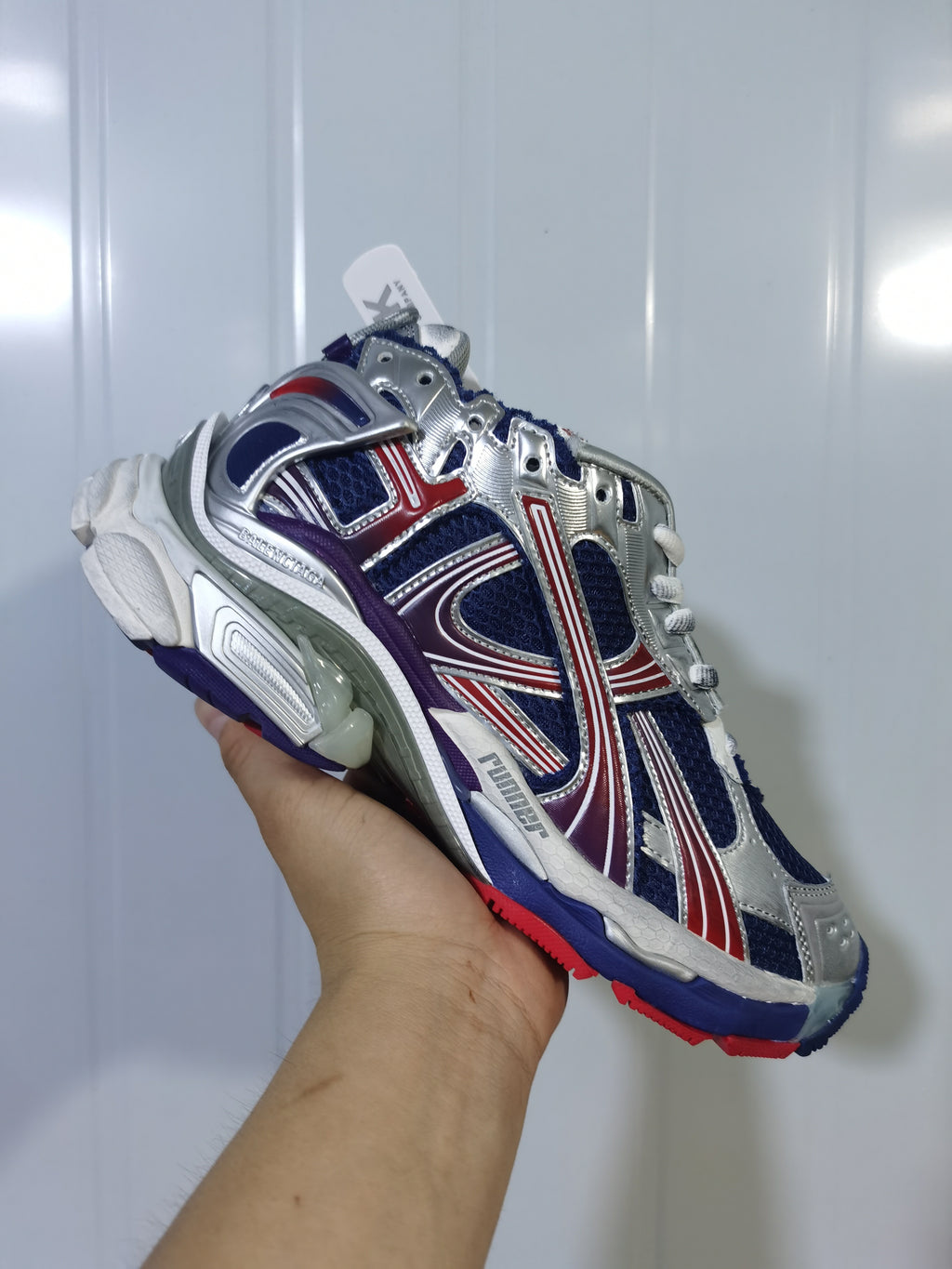 Close-up view of the royal blue, silver, red and white Balenciaga Runner sneaker, showing the layered upper and chunky sole.