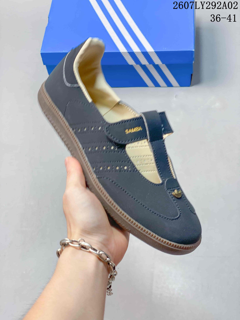 Angled side view of a dark navy Adidas Samba Jane shoe showing the T-strap, perforated panels, and gum-colored outsole.