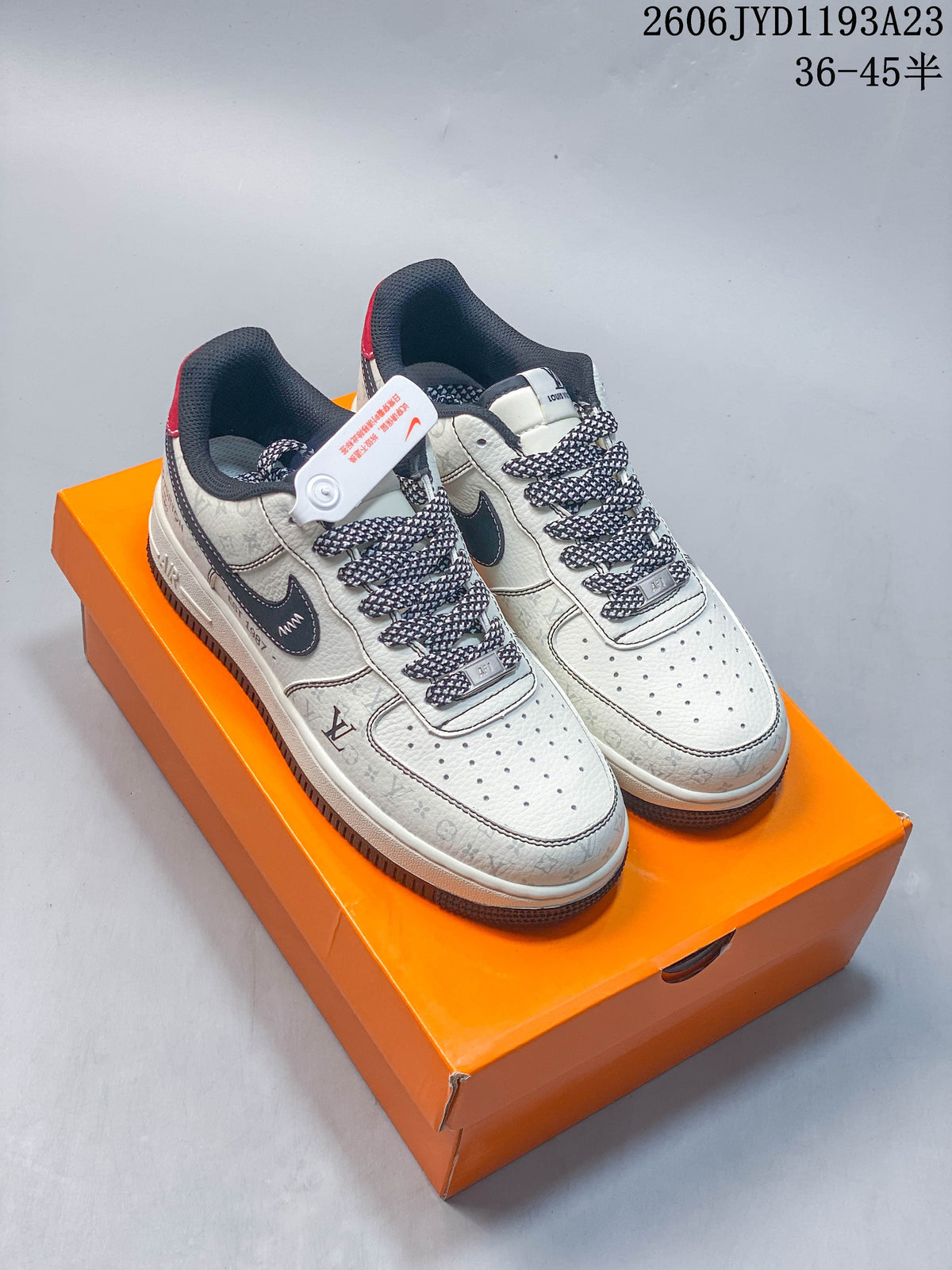 Pair of white and grey patterned low-top sneakers with dark side panels and red heel accents, shown on an orange box