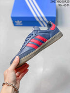 Side profile of the navy sneaker with red three-stripe detailing, stitched panels, and a gum-colored sole.