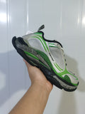 Close-up view of a grey and green Balenciaga Triple S 2 sneaker showing layered panels, mesh sections, black trim, and a chunky outsole.
