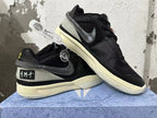 Angled view of black Nike basketball shoes showing mesh panels, dark Swoosh, and pale soles