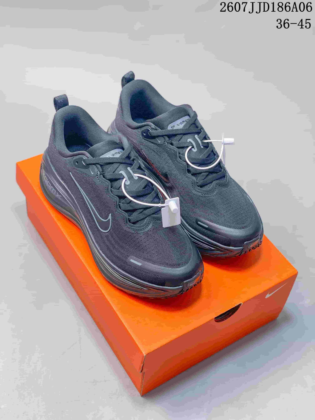 Pair of dark Nike Vomero 18 GTX sneakers displayed on an orange shoebox.