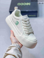 Angled close-up of the white ECCO sneaker showing the green side emblem, lace-up front and thick textured sole.