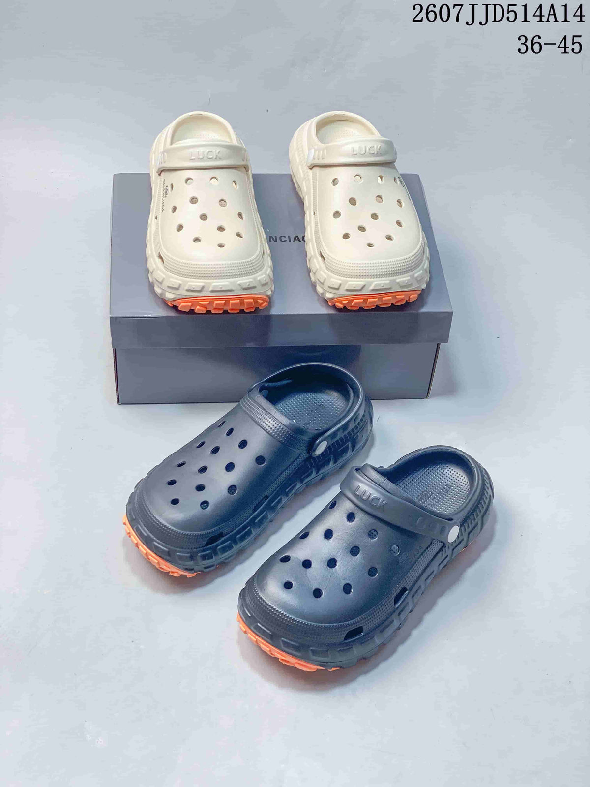 White and black pairs of perforated clogs shown together, each with adjustable straps and orange outsole accents.