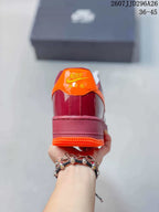 Rear view of a burgundy sneaker with an orange heel tab, orange outsole edge, and Nike Air branding.