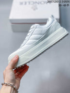 Side profile of the white lace-up sneaker showing layered panels, raised midsole and toothed outsole edge.