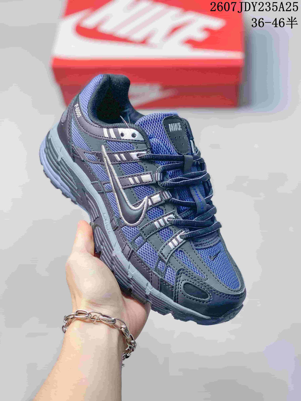Side view of a dark gray and blue-toned Nike P-6000 sneaker showing layered panels and a textured outsole.