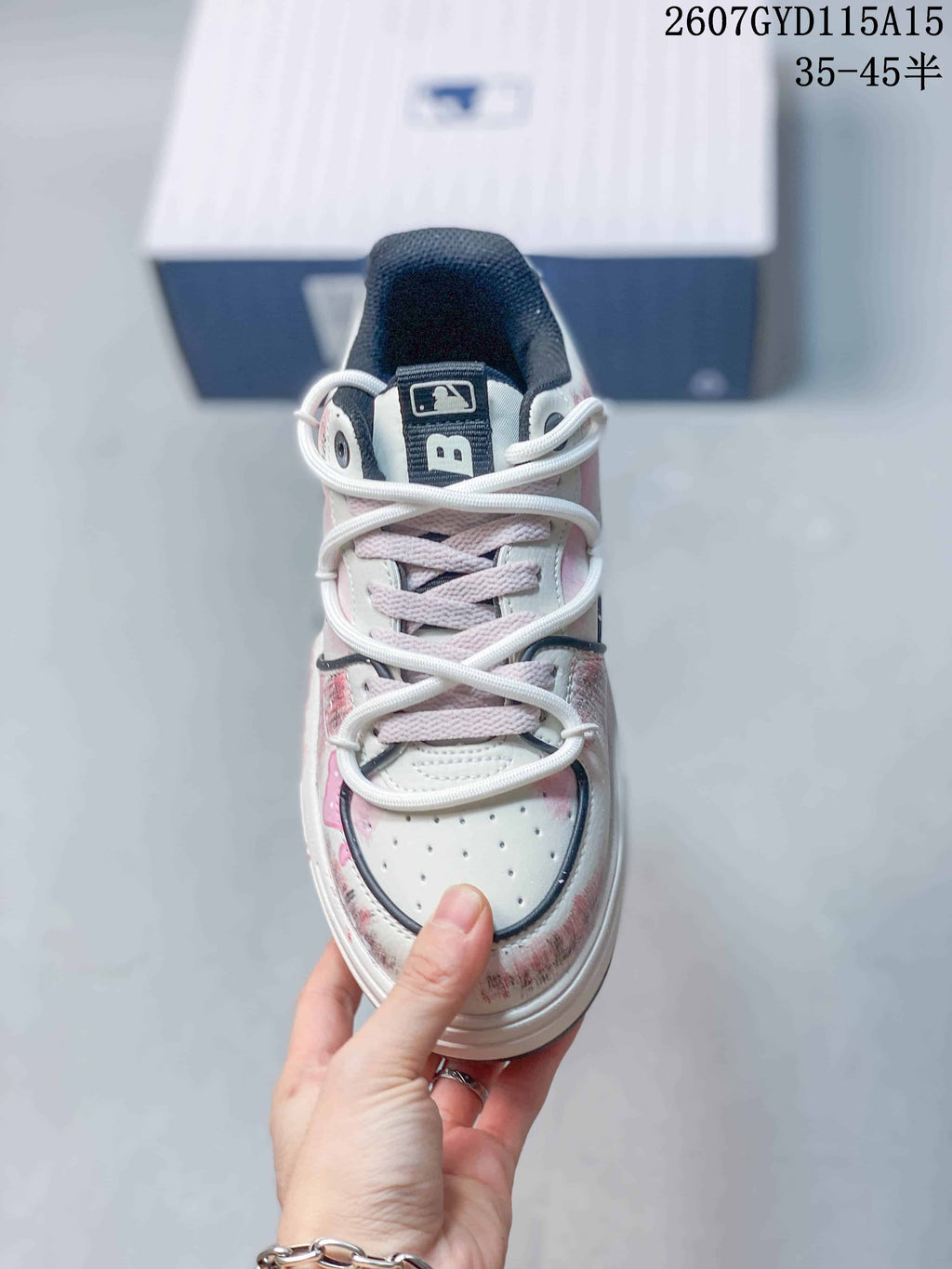 Top view of the sneaker showing pale pink laces, perforated white toe panels and branded tongue details.
