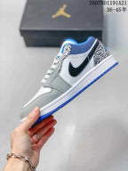 Side profile showing the black Swoosh, white quarter panel, grey overlays, elephant-print eyestay and blue outsole.