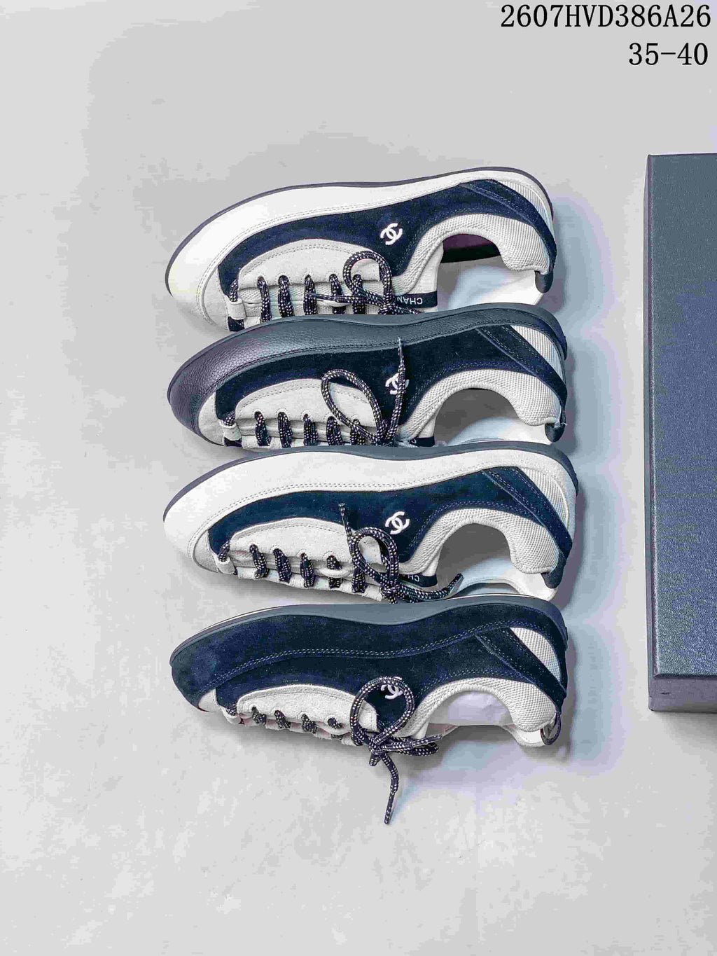 Top-down view of multiple black and white sneakers arranged beside a dark shoe box.