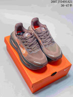 Pair of brown Nike Air Pegasus Premium sneakers with orange accents shown on an orange shoe box.