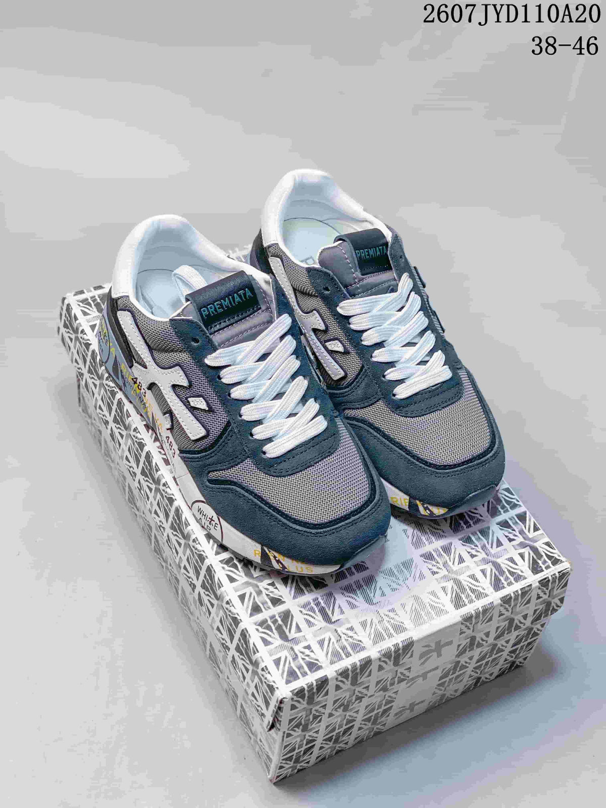 Pair of Premiata navy and gray retro sneakers displayed on a patterned shoebox.