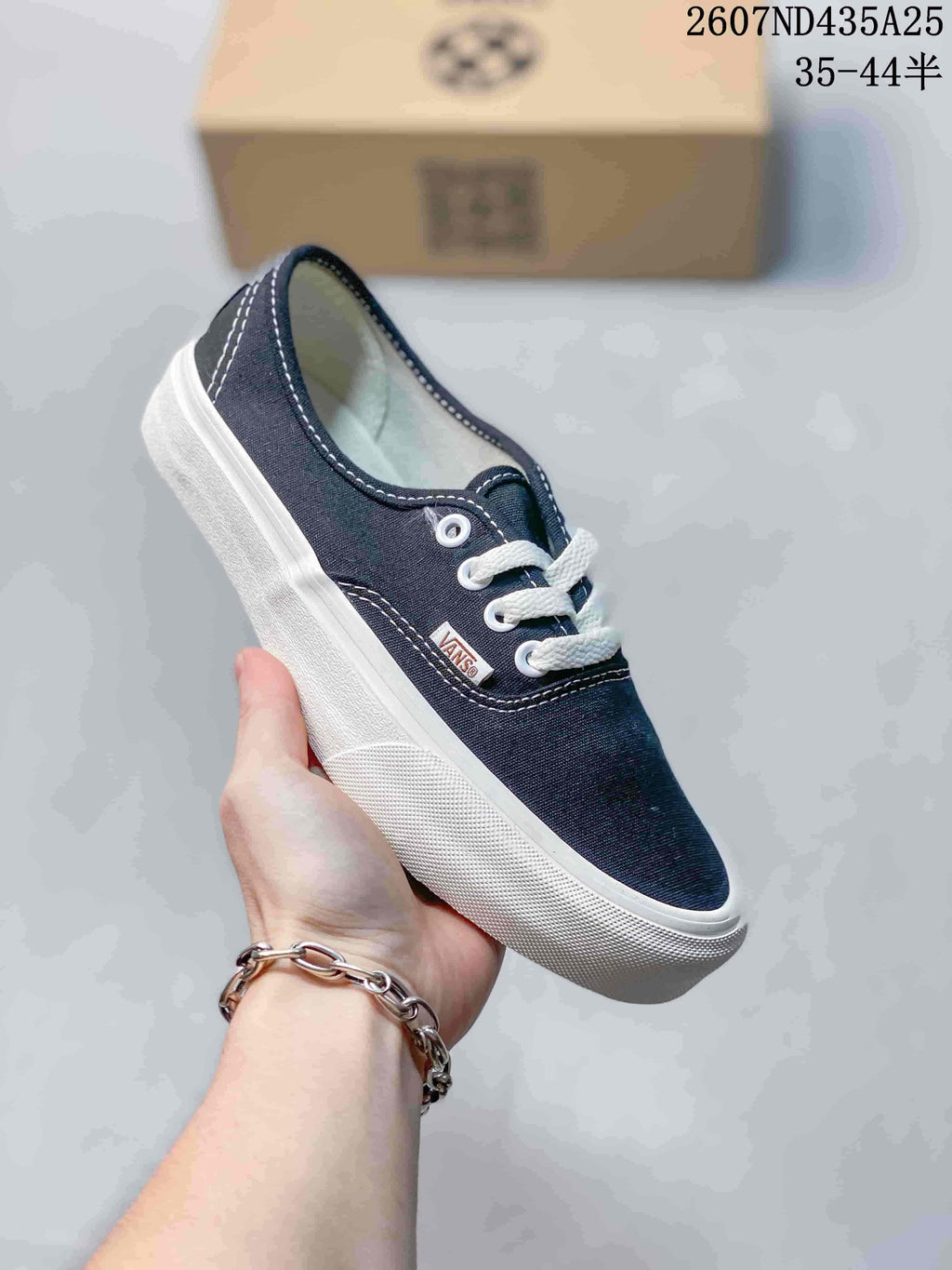Close-up of a navy canvas lace-up sneaker with white laces, contrast stitching, and a white rubber sidewall.