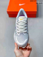 Top view of a light gray Nike running shoe showing the lace-up closure, perforated toe area, and yellow tongue branding.